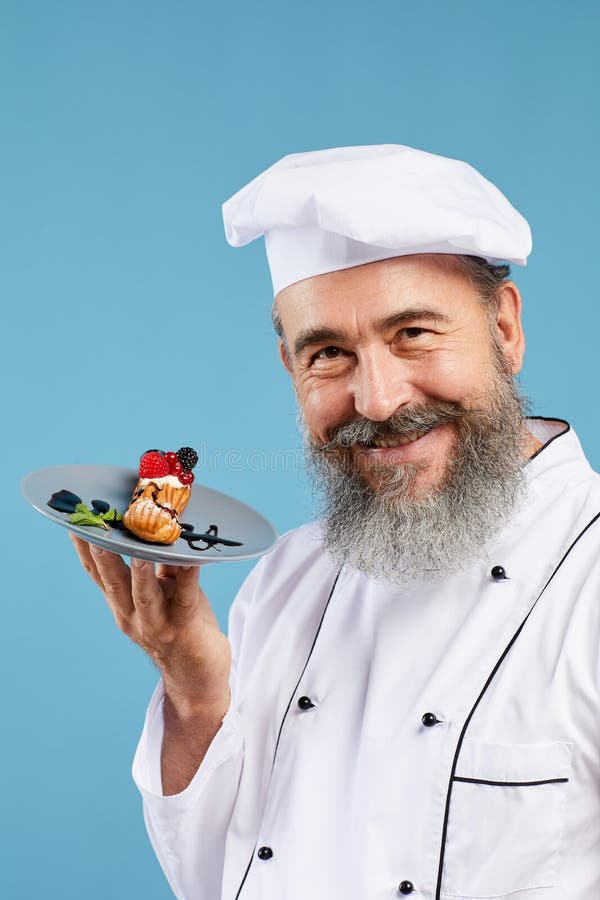 Smiling Senior Chef Holding Dessert on Blue stock photos Smiling Senior Chef Holding Dessert on Blue stock photos
