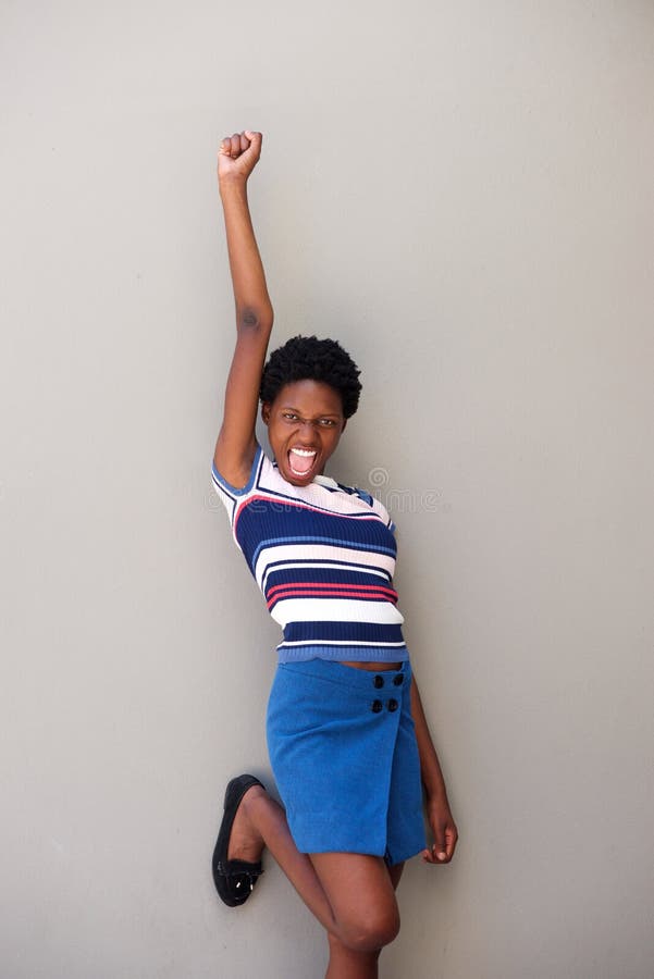 Cheerful young african woman laughing with arm raised against gray background royalty free stock photo Cheerful young african woman laughing with arm raised against gray background royalty free stock photo