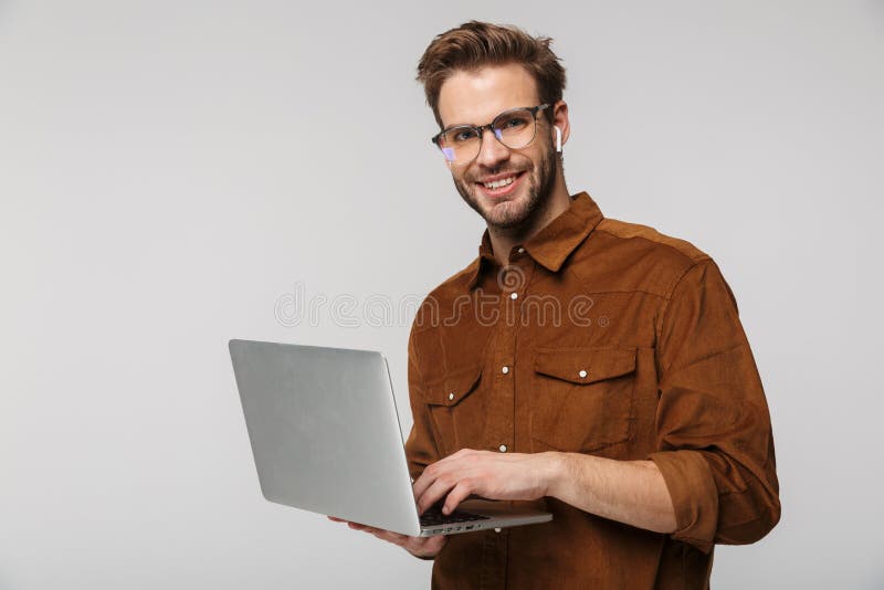 Portrait of cheerful young man using laptop and earphone