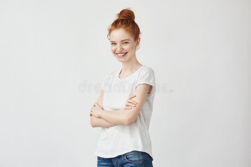 Portrait of cheerful young redhead girl laughing with crossed arms.