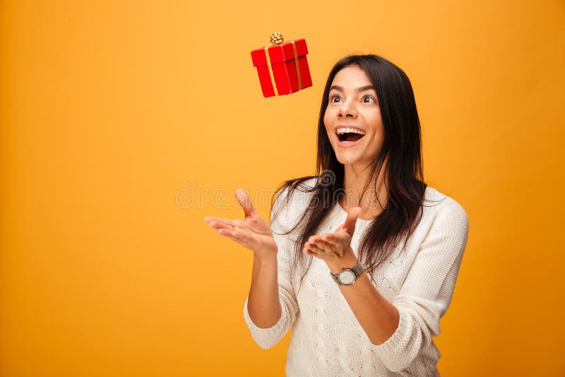 Portrait of a cheerful young woman catching small gift box