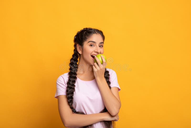 Portrait of a cheerful young woman eating green apple