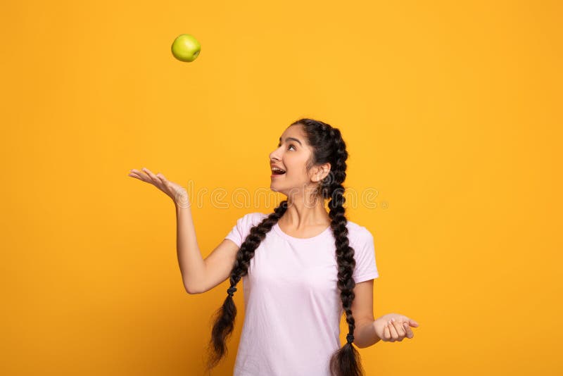 Portrait of a cheerful young woman juggling green apple