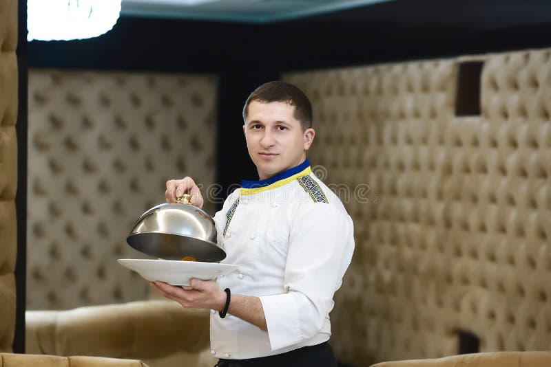Portrait chef presenting a dish at the hotel restaurant, steaming a dish with a cover lid royalty free stock photo Portrait chef presenting a dish at the hotel restaurant, steaming a dish with a cover lid royalty free stock photo