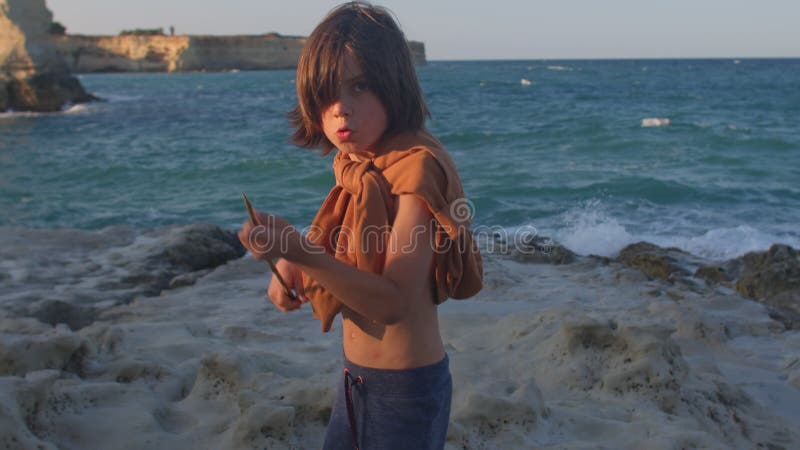 Portrait of a child at the sea. He holds in his hands a spear. Survival game.