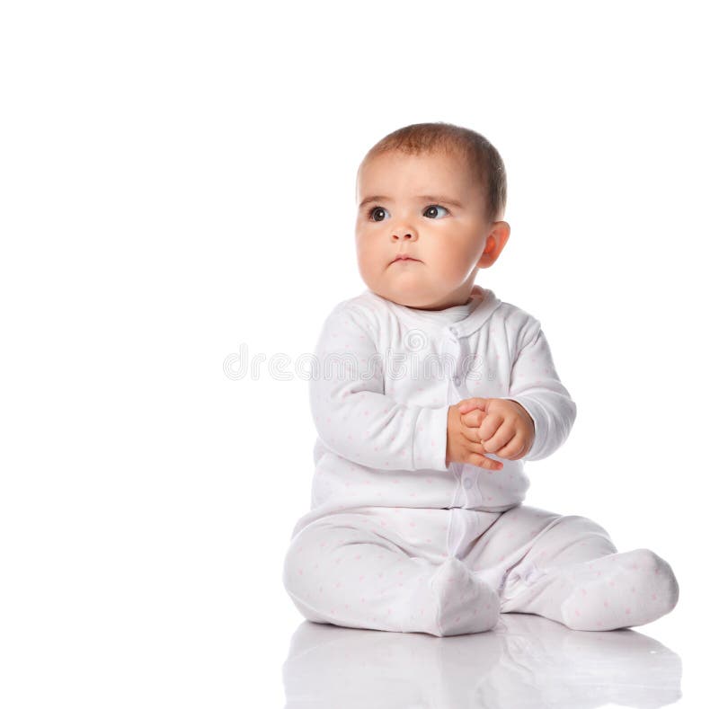 Portrait of a concerned child sitting in the studio on a white background. Little girl dressed in a white bodysuit looking at free space for text. Place for stock photography Portrait of a concerned child sitting in the studio on a white background. Little girl dressed in a white bodysuit looking at free space for text. Place for stock photography