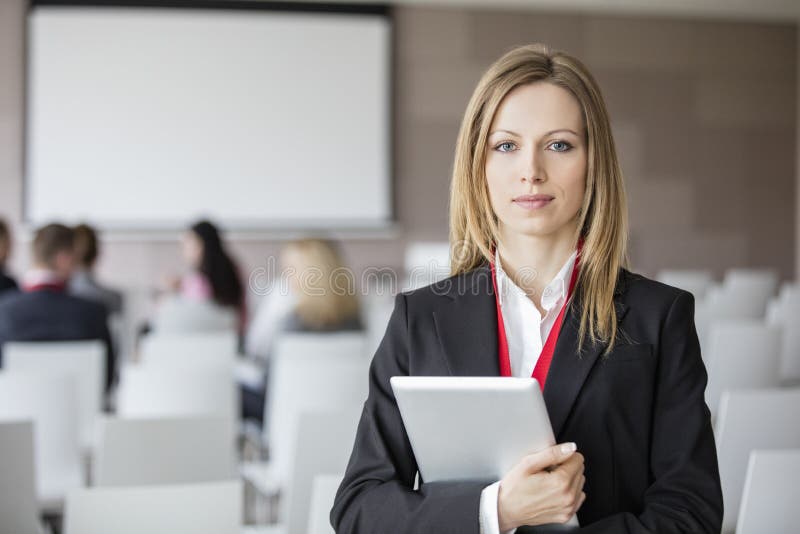 Portrait of confident businesswoman holding digital tablet in seminar hall royalty free stock images Portrait of confident businesswoman holding digital tablet in seminar hall royalty free stock images