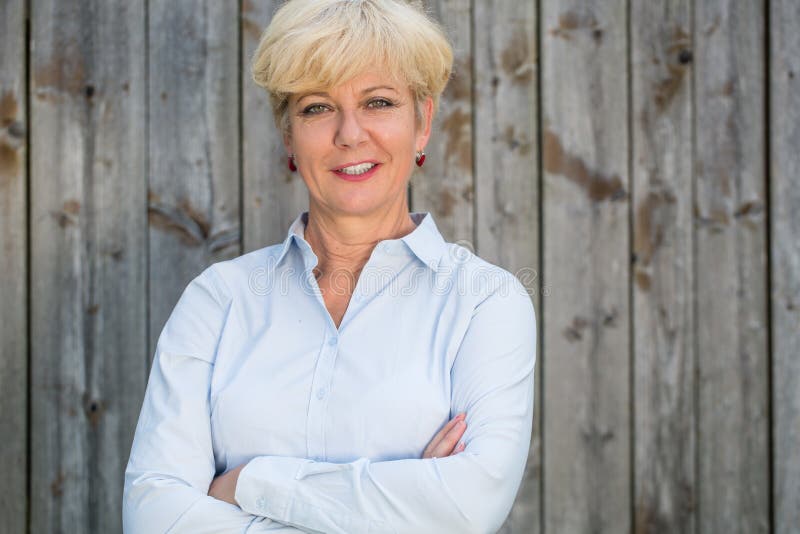 Portrait of a confident senior woman looking at camera against a