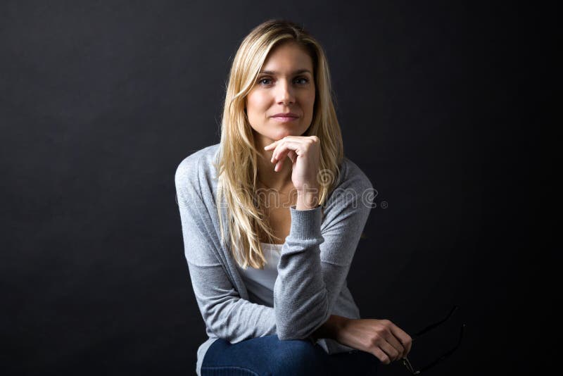 Confident young woman looking at camera over black background