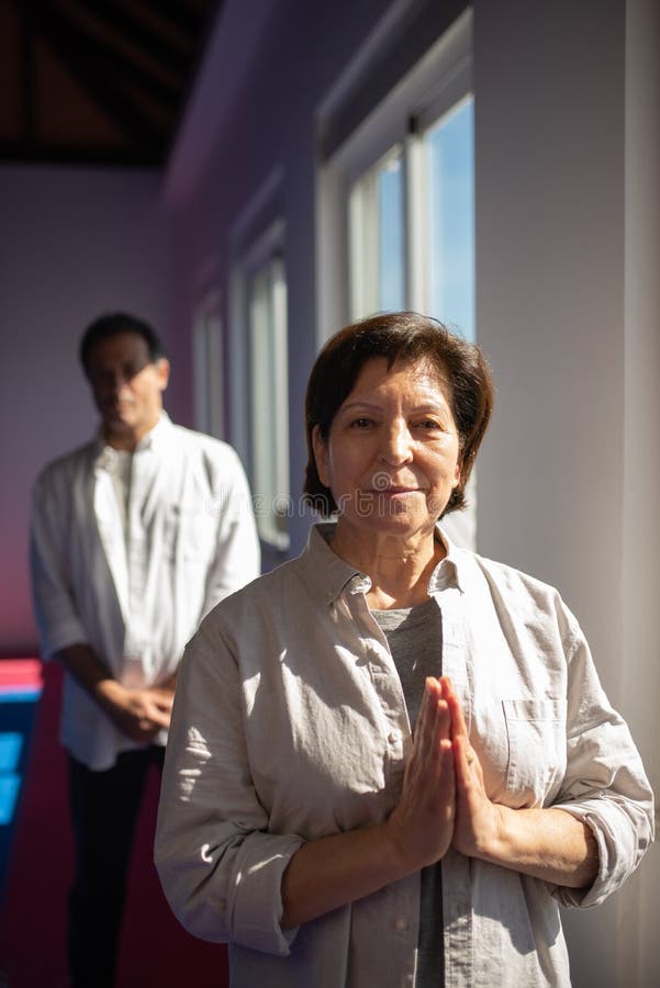 Portrait of content Asian yoga coach in gym. Senior woman in shirt holding hands in Namaste. Meditation concept. Qigong class stock images, royalty-free photos and pictures