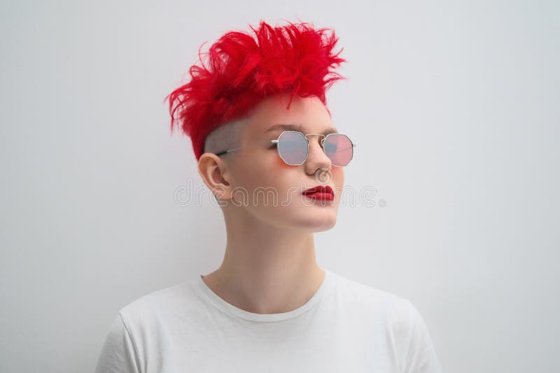 Portrait of a cool fashionable modern young girl. A short haircut with shaved temple. Dyed bright red hair. Red lipstick stock photos Portrait of a cool fashionable modern young girl. A short haircut with shaved temple. Dyed bright red hair. Red lipstick stock photos