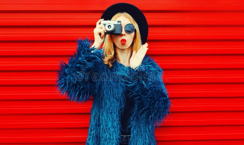 Portrait cool surprised woman with retro camera taking picture wearing blue faux fur coat, round hat and sunglasses royalty free stock photography Portrait cool surprised woman with retro camera taking picture wearing blue faux fur coat, round hat and sunglasses royalty free stock photography