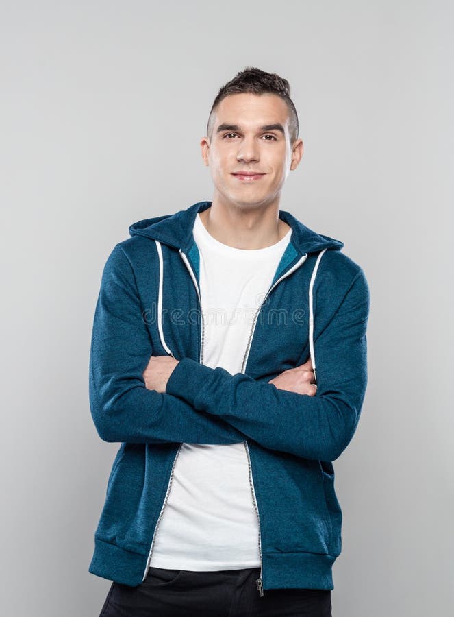 Portrait of young man wearing hoodie with his arms crossed stock