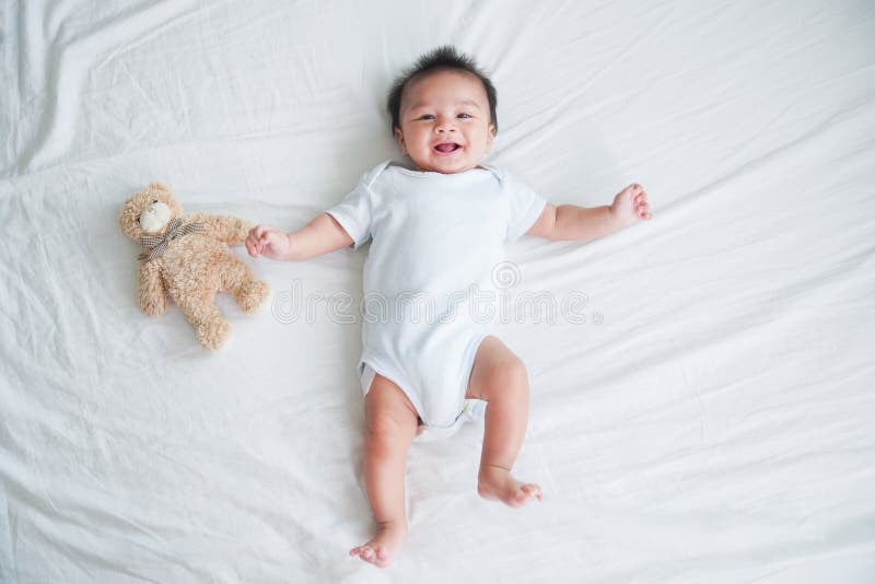 Portrait of a crawling baby on the bed in her room, Adorable baby boy in white sunny bedroom, Newborn child relaxing in bed