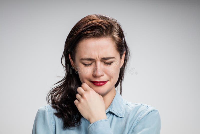 The portrait of a crying young lonely woman on gray stock photos The portrait of a crying young lonely woman on gray stock photos