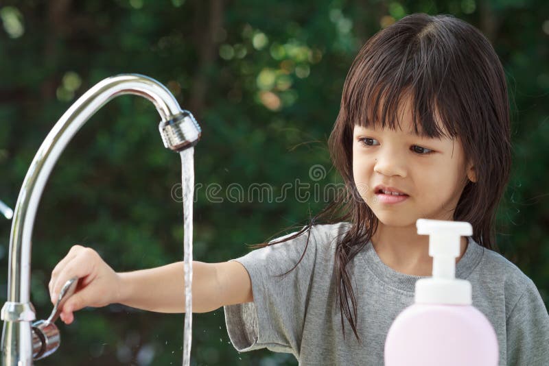 Portrait cute Asian girl aged 4 to 8 years old, washing her hands with soap from the tap. To clean her hands Frequent hand washing