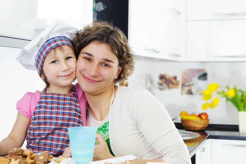 Portrait of cute girl and mother in kitchen stock images