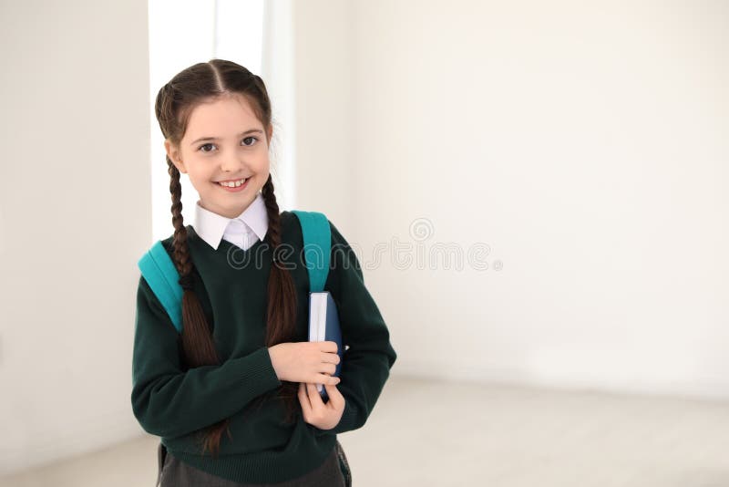 Portrait of cute girl in school uniform with backpack and book indoors royalty free stock photo Portrait of cute girl in school uniform with backpack and book indoors royalty free stock photo