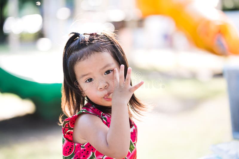 Portrait cute kid girl is sucking her fingers with candy crumbs on it. Child 3 years old. Empty space to enter text