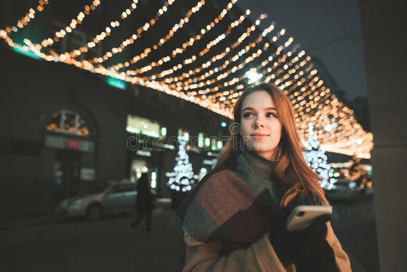 Portrait of a Cute Lady in Warm Clothing Uses a Smartphone,looks in the ...