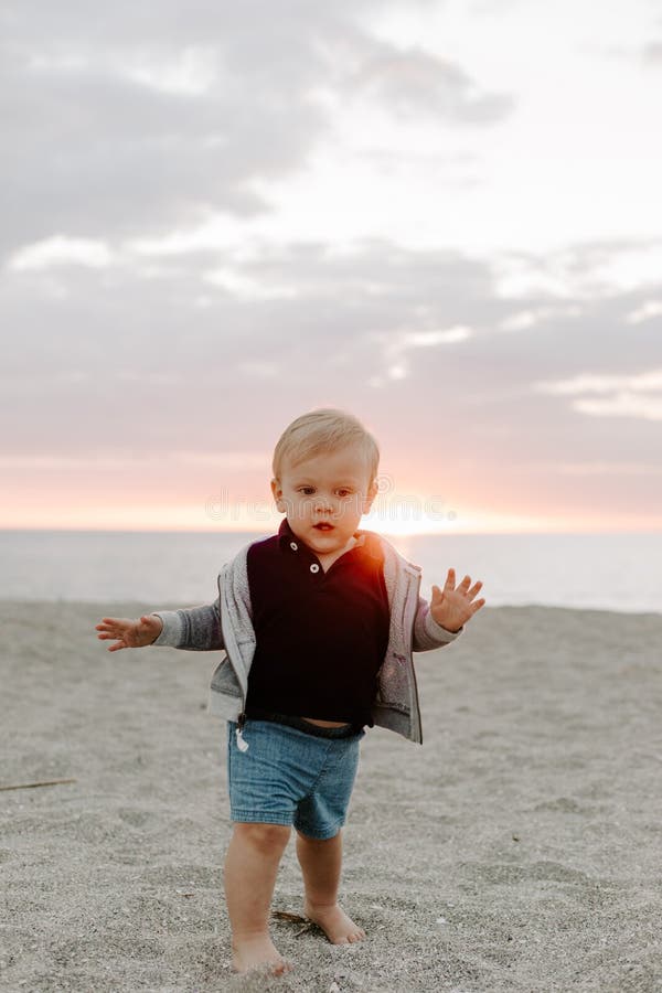 Portrait of Cute Little Baby Boy Child Playing and Exploring in the Sand at the Beach During Sunset Outside on Vacation in Hoodie royalty free stock photo Portrait of Cute Little Baby Boy Child Playing and Exploring in the Sand at the Beach During Sunset Outside on Vacation in Hoodie royalty free stock photo