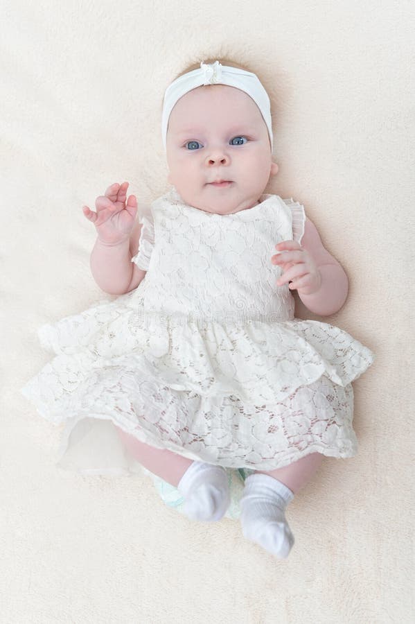 Cute Little Baby Girl in White Dress Lying on Bed Top View Stock Photo ...