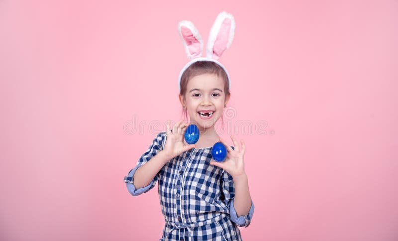 Portrait of a cute little girl with Easter eggs on a pink background