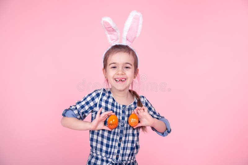 Portrait of a cute little girl with Easter eggs on a pink background