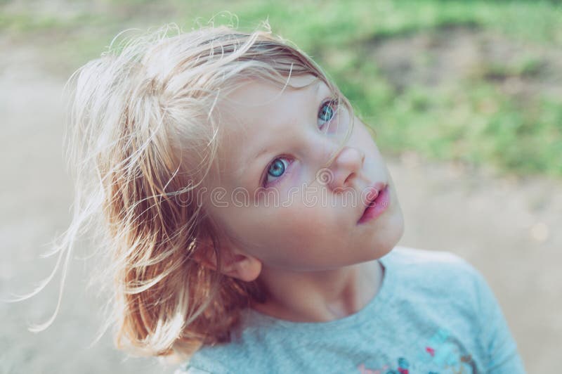 Portrait of a cute little girl with a serious facial expression looking to the side and up stock image