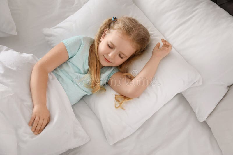 Portrait of cute little girl sleeping in large bed