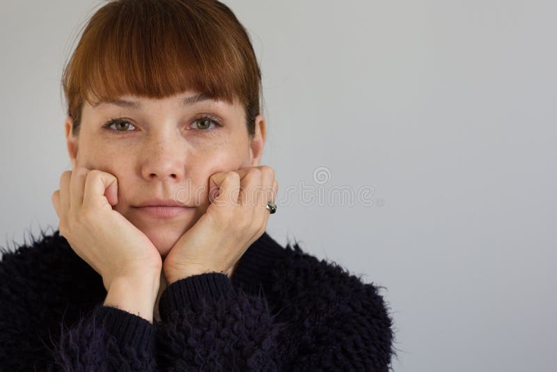 Portrait of the cute middle aged woman holding her hands close to face and looking at camera on white background