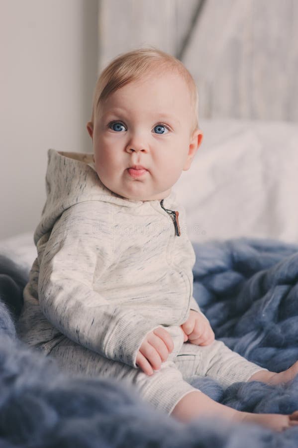 Portrait of Cute 8 Month Old Baby Sitting on the Bed on Knitted Blanket ...