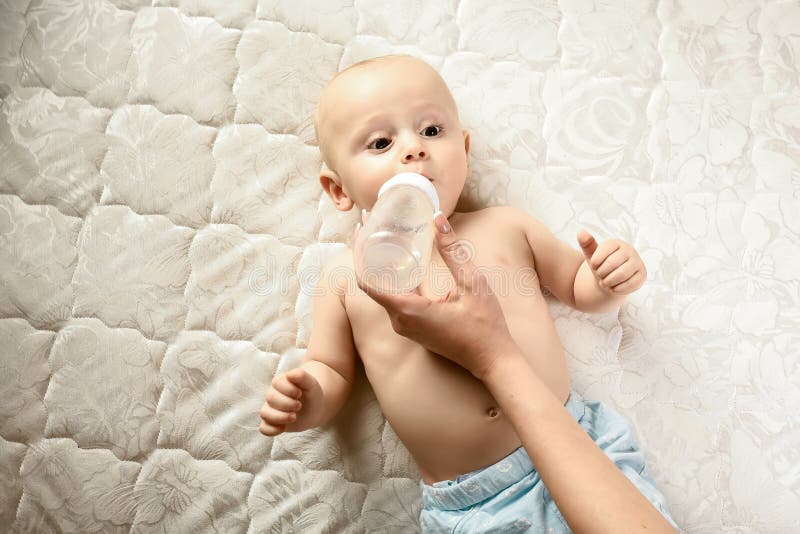 A portrait of cute newborn baby being fed by her mother using bottle. concept maternal care for baby stock photo A portrait of cute newborn baby being fed by her mother using bottle. concept maternal care for baby stock photo