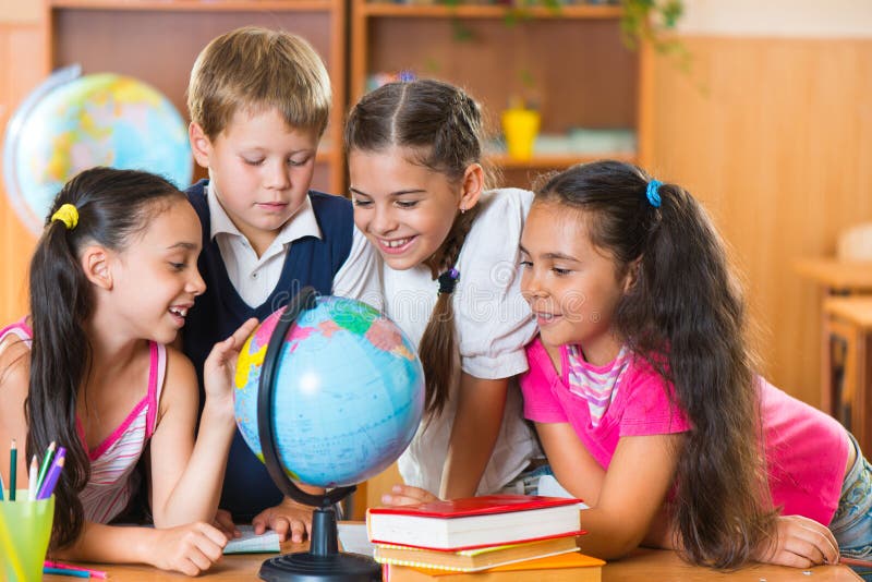 Portrait of cute schoolchildren looking at globe stock images