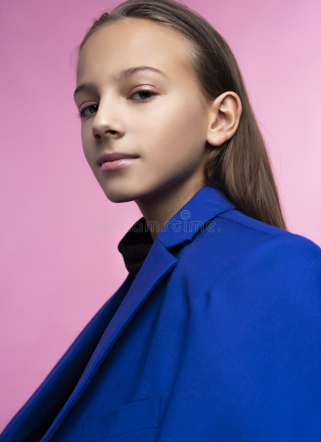Portrait of a cute smiling teen girl wearing a dark turtleneck and a blue jacket blazer. Pink background. Advertising, trendy and stock image Portrait of a cute smiling teen girl wearing a dark turtleneck and a blue jacket blazer. Pink background. Advertising, trendy and stock image