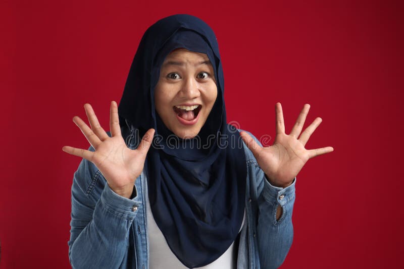 Portrait of cute young Asian muslim lady wearing hijab shows surprised or shocked expression with big eyes and open mouth