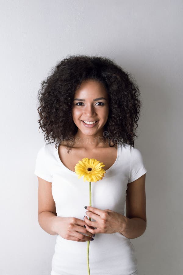 Portrait of cute young woman holding a yellow flower