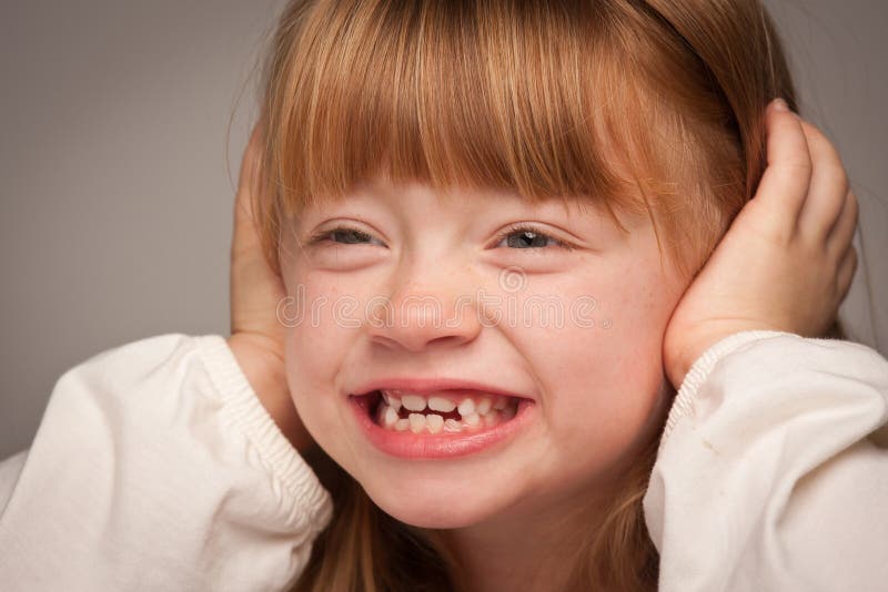 Portrait d'amusement d'une fille d'une chevelure rouge adorable sur le gris image libre de droits Portrait d'amusement d'une fille d'une chevelure rouge adorable sur le gris image libre de droits