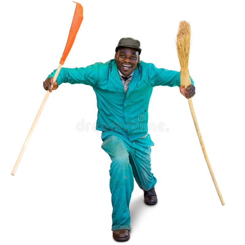Full length portrait of happy dancing african garden worker in green overall. Man holding broom and rake isolated on white background. Full length portrait of happy dancing african garden worker in green overall. Man holding broom and rake isolated on white background.