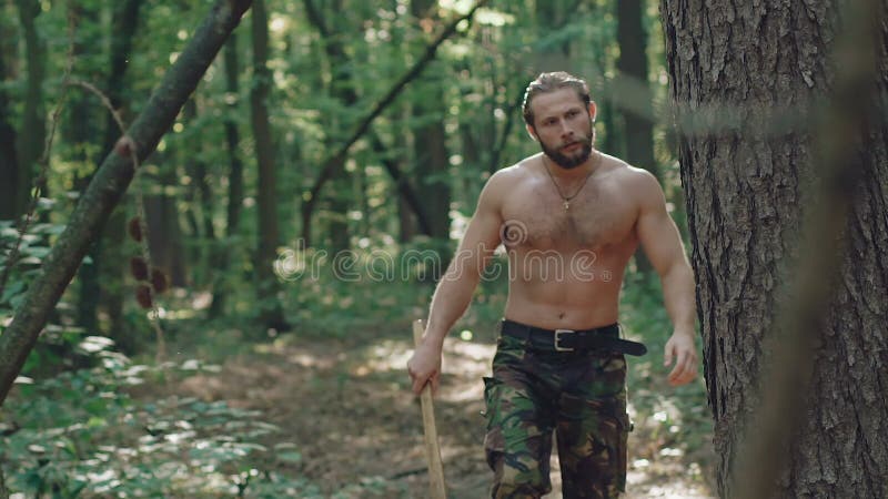Portrait d'homme barbu bel avec la hache dans la forêt lentement