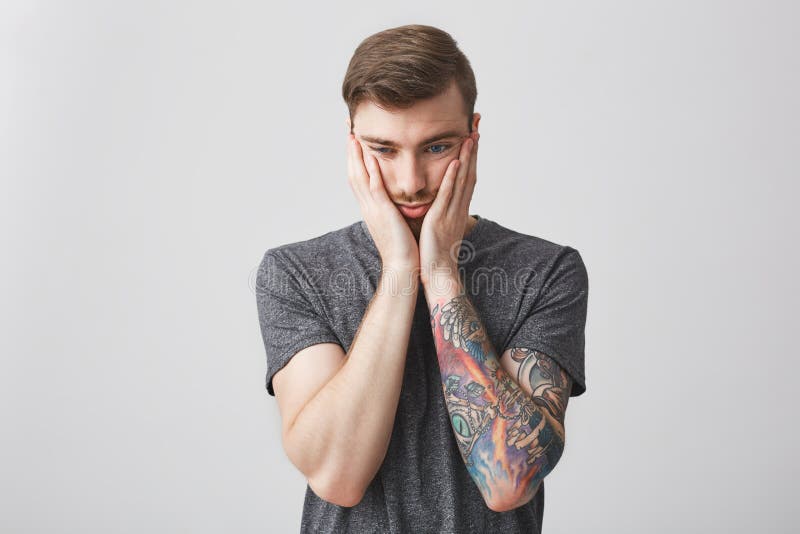 Portrait d'homme barbu caucasien bel avec la coiffure élégante et de tatouage sur le bras gauche étant fatigué et contrarié ensui photographie stock Portrait d'homme barbu caucasien bel avec la coiffure élégante et de tatouage sur le bras gauche étant fatigué et contrarié ensui photographie stock