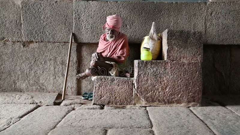 Portrait d'homme indien dans des vêtements colorés se reposant sur les escaliers en pierre dans Hampi