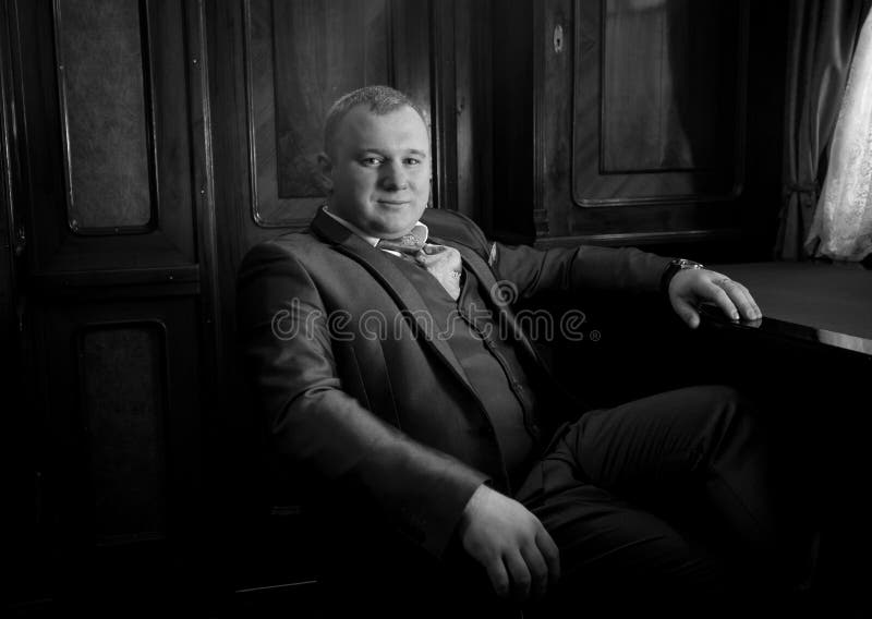 Portrait d'homme élégant dans le rétro costume se reposant dans le fauteuil à photos stock Portrait d'homme élégant dans le rétro costume se reposant dans le fauteuil à photos stock