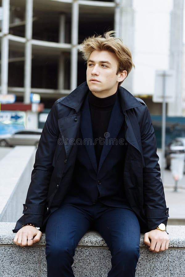 Portrait d'un beau, attrayant, jeune homme dans un costume bleu, manteau, dans la ville songeur et triste, attendant image stock Portrait d'un beau, attrayant, jeune homme dans un costume bleu, manteau, dans la ville songeur et triste, attendant image stock