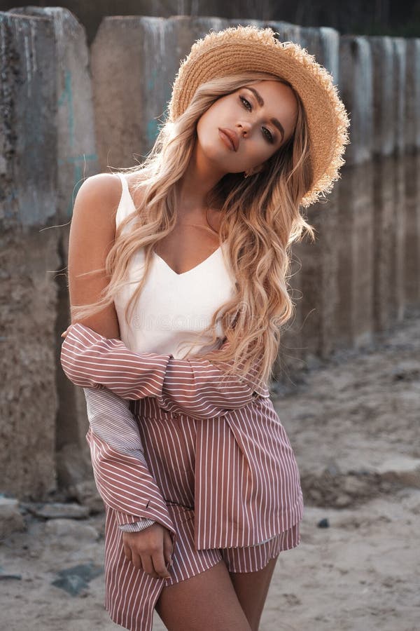 Portrait d'un beau, romantique et élégant modèle femelle avec de longs cheveux blonds lâches dans un chapeau de paille Paysage de images libres de droits Portrait d'un beau, romantique et élégant modèle femelle avec de longs cheveux blonds lâches dans un chapeau de paille Paysage de images libres de droits