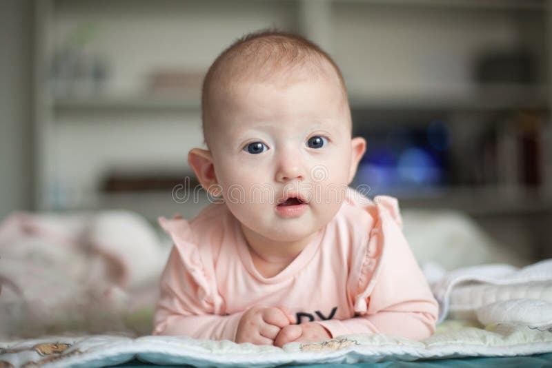 Portrait d'un bébé avec du charme se trouvant sur son estomac Matin de famille ? la maison Temps de ventre photographie stock Portrait d'un bébé avec du charme se trouvant sur son estomac Matin de famille ? la maison Temps de ventre photographie stock