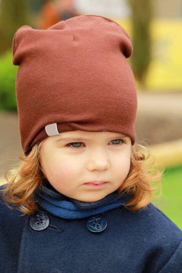 Portrait d'un un bébé an sérieux élégant mignon utilisant un manteau bleu-foncé, l'écharpe et un chapeau brun un bel automne enso photographie stock libre de droits Portrait d'un un bébé an sérieux élégant mignon utilisant un manteau bleu-foncé, l'écharpe et un chapeau brun un bel automne enso photographie stock libre de droits