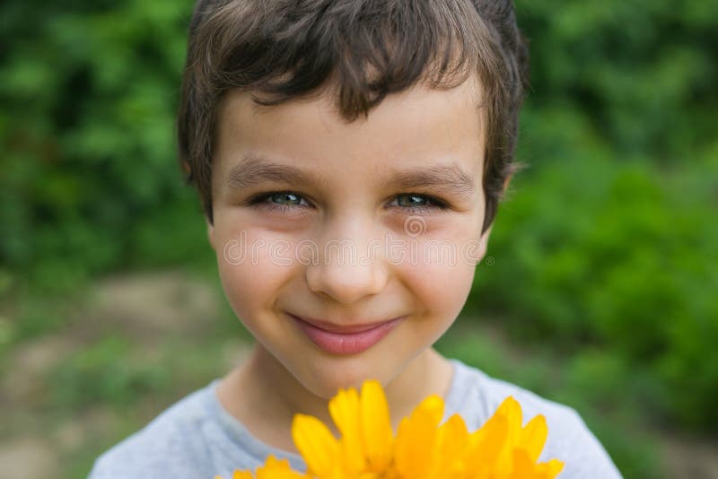 Portrait d'un garçon de sourire mignon avec une fleur jaune images libres de droits Portrait d'un garçon de sourire mignon avec une fleur jaune images libres de droits