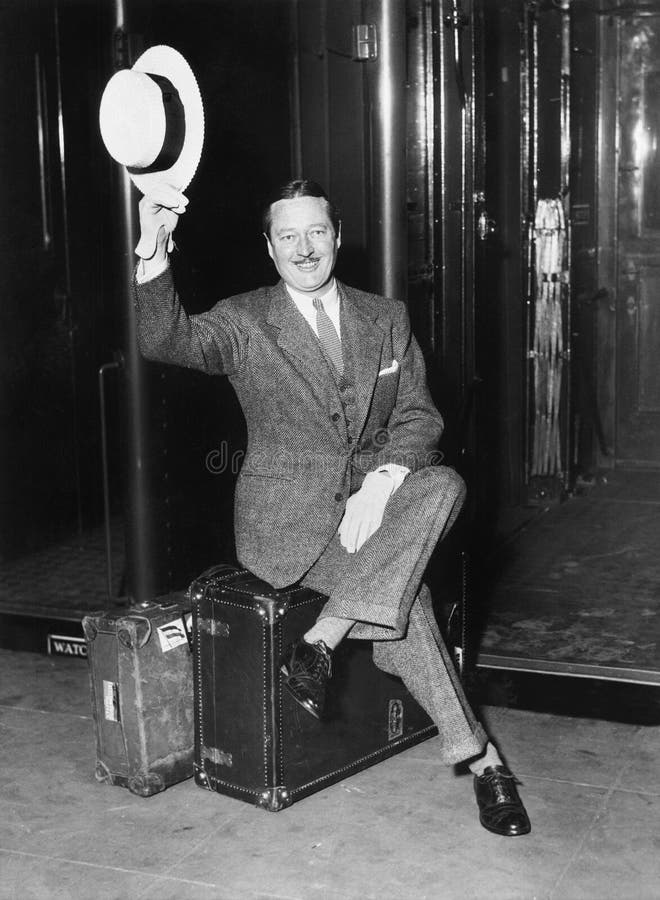 Portrait d'un homme d'affaires s'asseyant sur ses valises sur une plate-forme devant un train (toutes les personnes représentées image libre de droits Portrait d'un homme d'affaires s'asseyant sur ses valises sur une plate-forme devant un train (toutes les personnes représentées image libre de droits