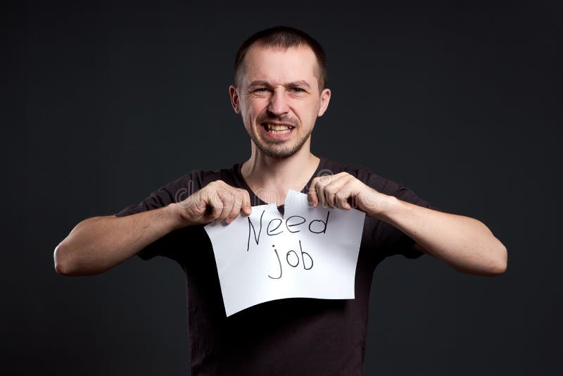 Portrait d'un homme déchirant une inscription sur le papier d'avoir besoin d'un boulot images stock